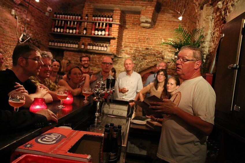 Un grupo de personas en un bar, con una pared de ladrillo y estantes llenos de botellas al fondo. 2