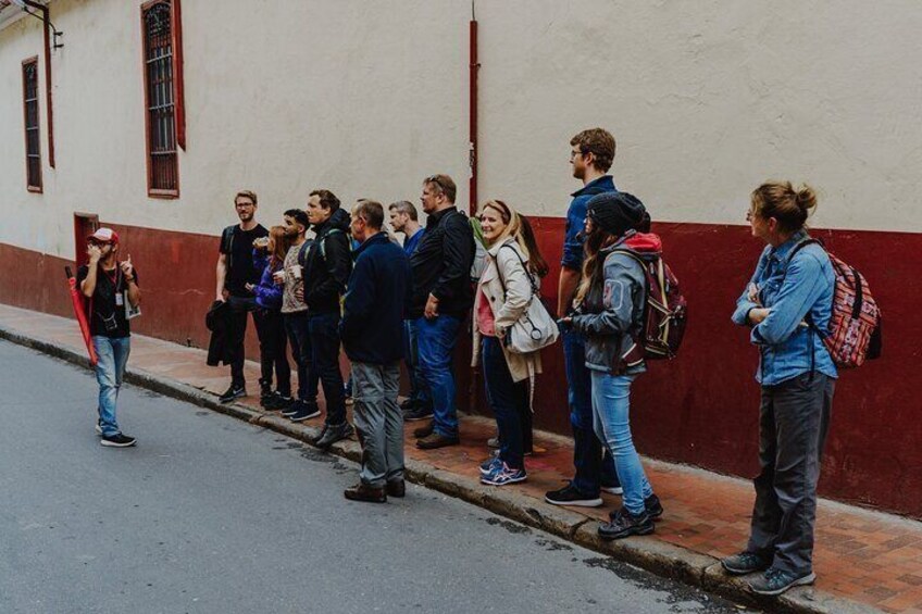 A group of people standing on a sidewalk next to a building with a red and white facade. 4