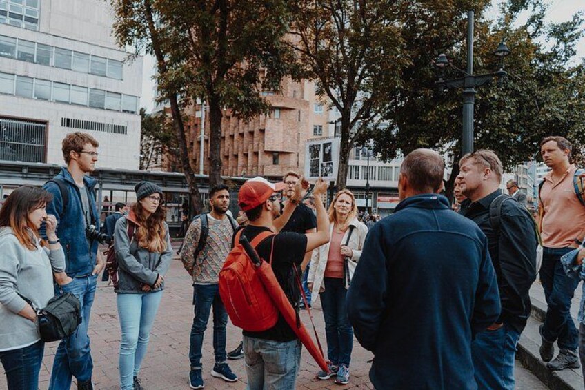 A group of people standing on a city sidewalk, engaged in conversation. 1