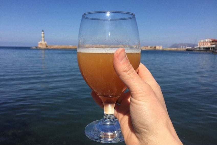 A hand holding a glass of amber liquid, with a lighthouse and calm sea in the background. 3
