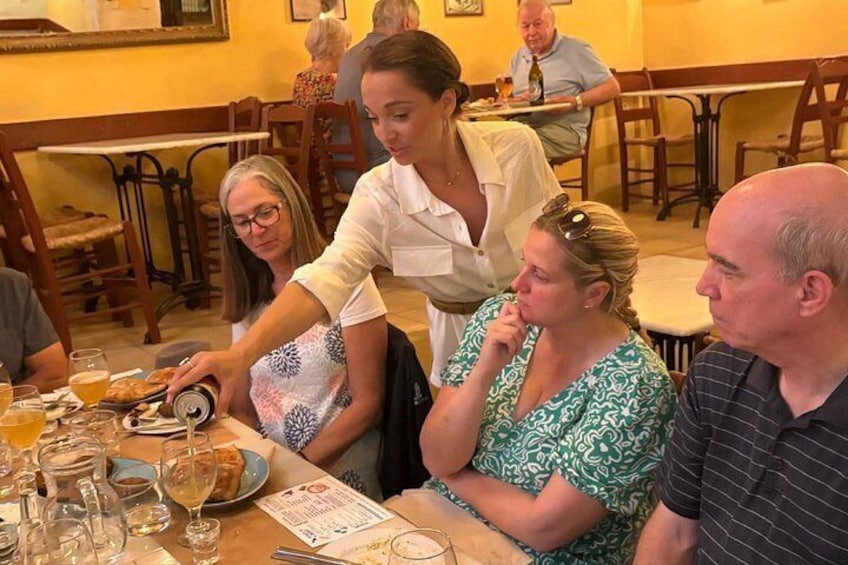 Een restaurantscène met etende gasten, een ober die een tafel bedient en een menukaart op tafel. 5