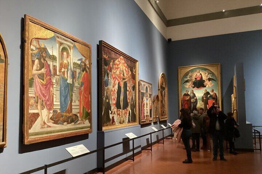 Et museumsinteriør med store indrammede malerier på væggene. 5