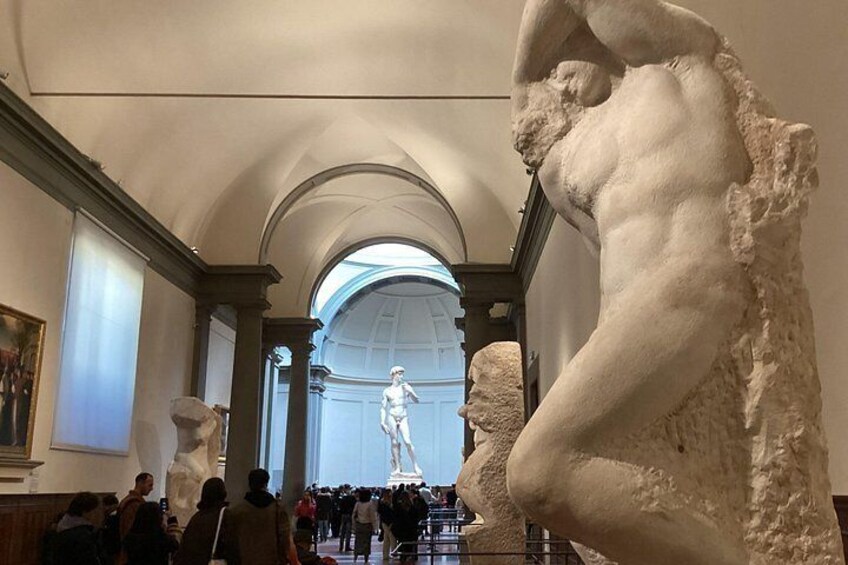 A museum interior with classical sculptures and a large arched doorway. 2