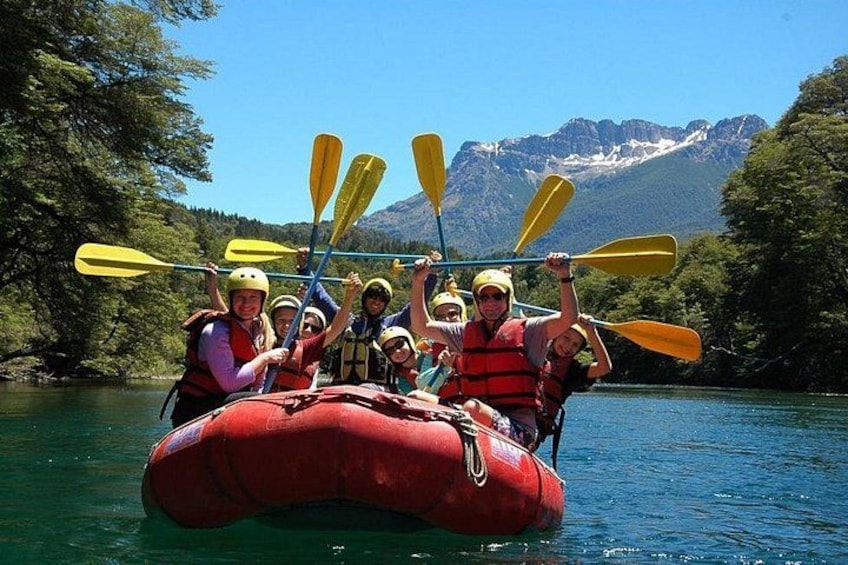 A group of people in a red raft on a river with mountains in the background. 3