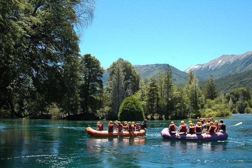 A group of people rafting on a river surrounded by trees and mountains. 5