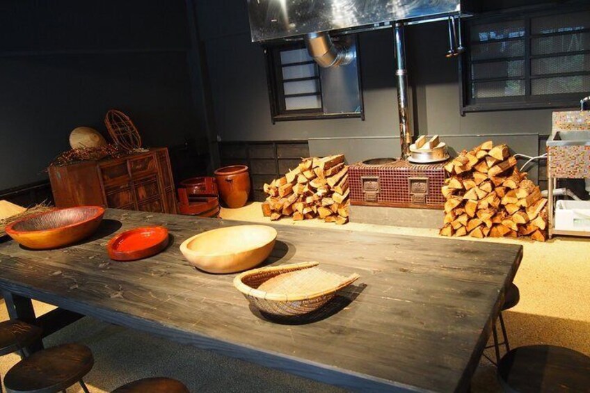 A rustic kitchen with wooden tables, bowls, and stacked firewood. 4
