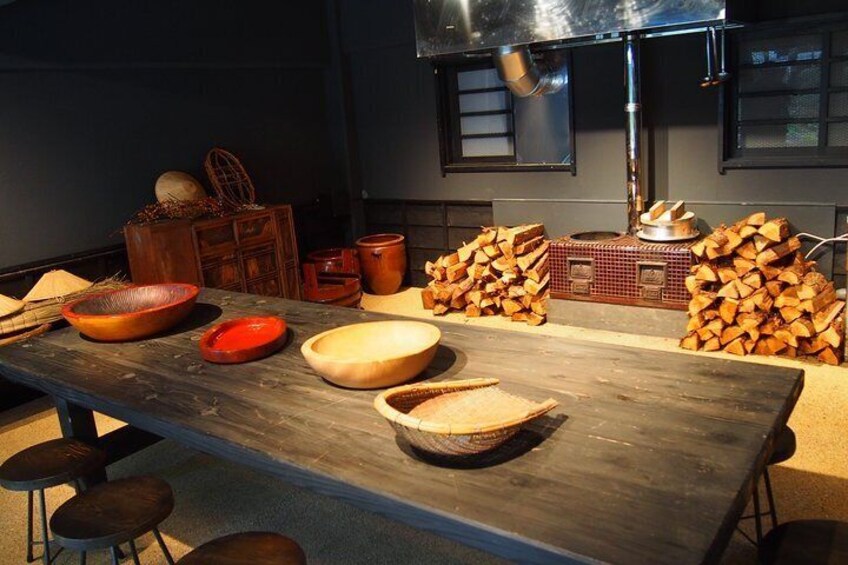 A rustic kitchen with wooden tables, bowls, and stacked firewood. 2