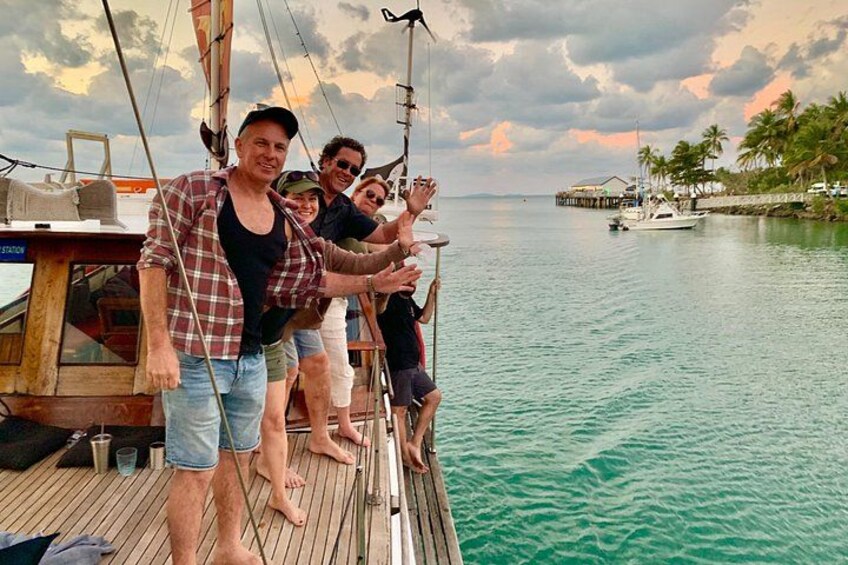 A group of people on a boat with a dock and palm trees in the background. 3