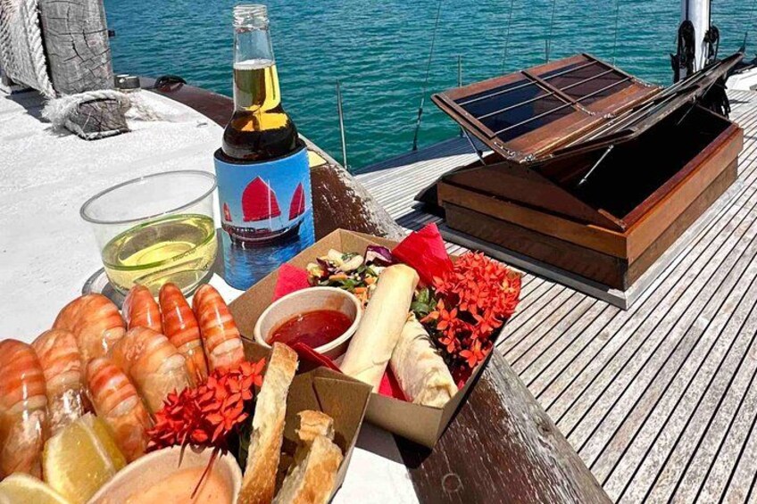 A wooden deck with a table set with food, a bottle, and a solar-powered device. 5