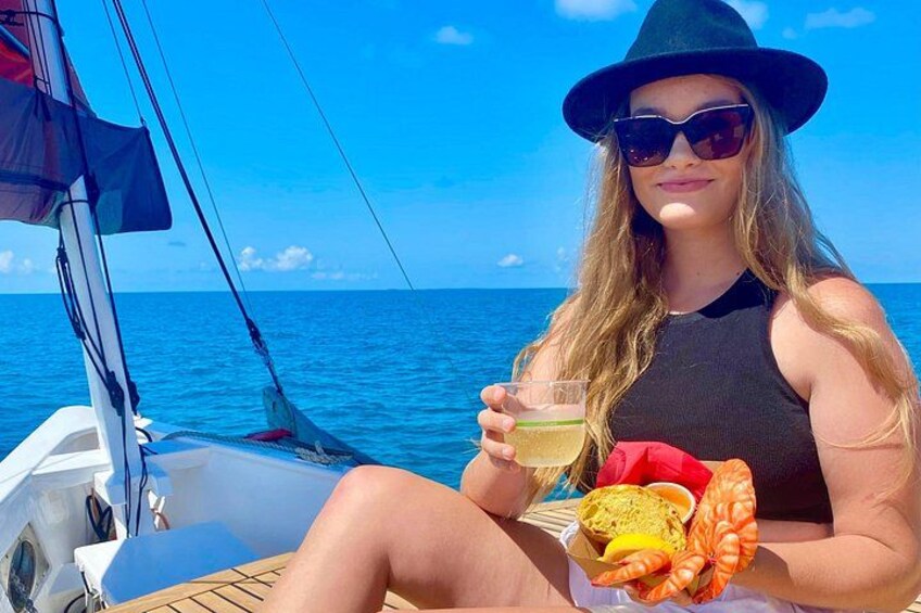 A person on a boat holding a drink and a crab. 1