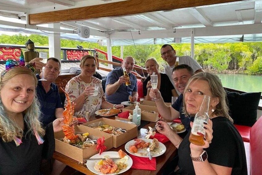 A group of people dining on a boat with seafood and drinks. 4