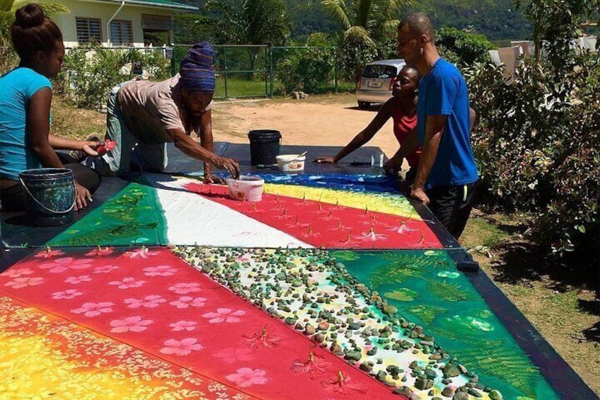 People painting a large, colorful quilt outdoors. 4