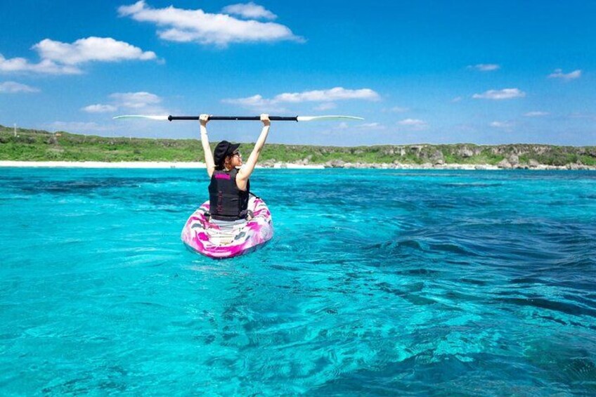 A person on a paddleboard in turquoise water with a clear sky. 3