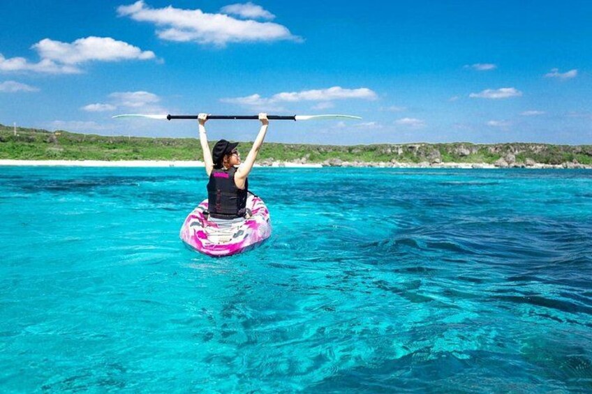 Une personne sur une planche à pagaie, dans une eau turquoise, sous un ciel dégagé. 3