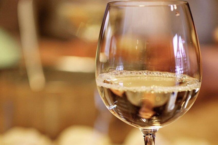 A close-up of a wine glass with a clear liquid, likely wine, and a small amount of foam on the surface. 4