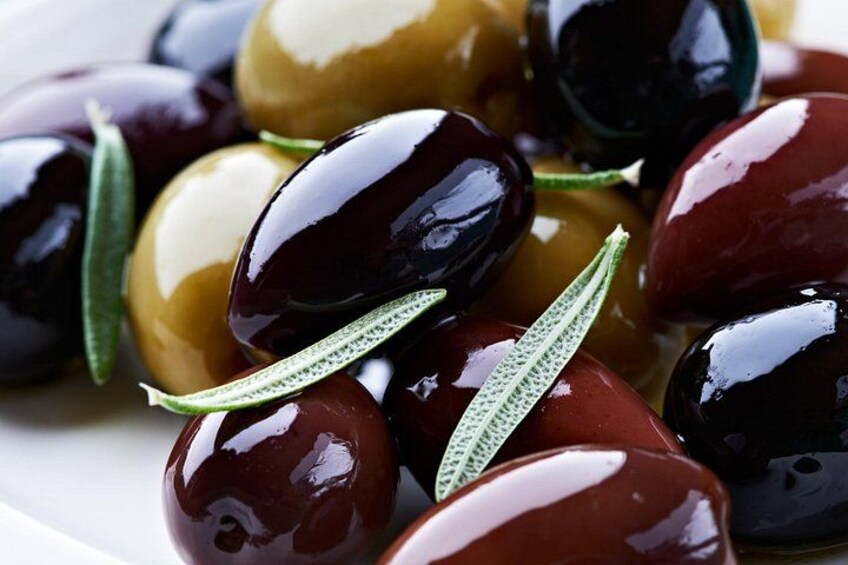 A plate of olives with green leaves. 5