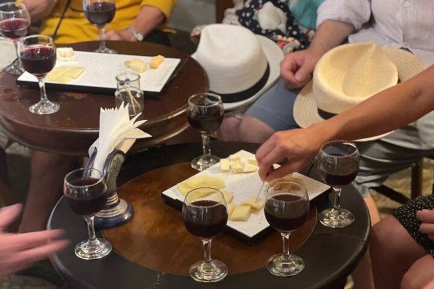 People seated at round tables with wine glasses and cheese plates. 3