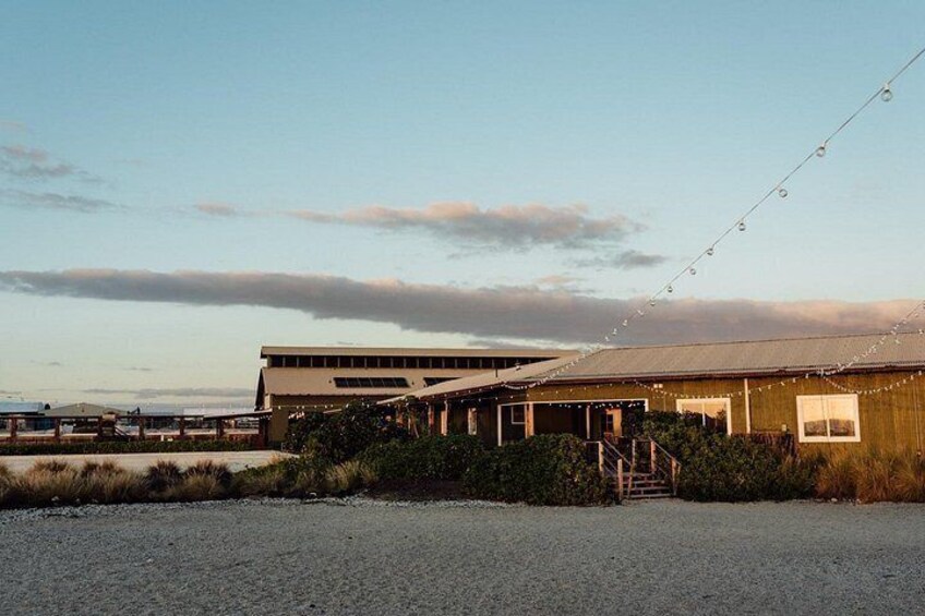 A building with a sloped roof, a gravel driveway, and a string of lights. 2