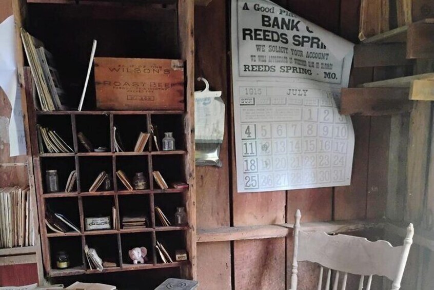 A wooden interior with a calendar, a shelf with various items, and a chair. 2