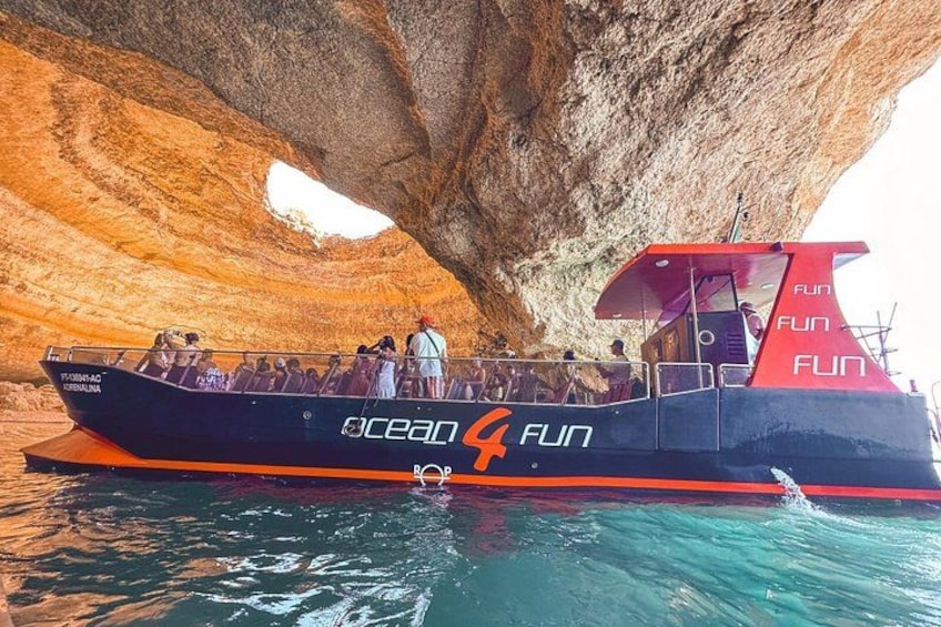 Een boot met 'Ocean 4 Fun'-logo, afgemeerd onder een grote rotsformatie. 1