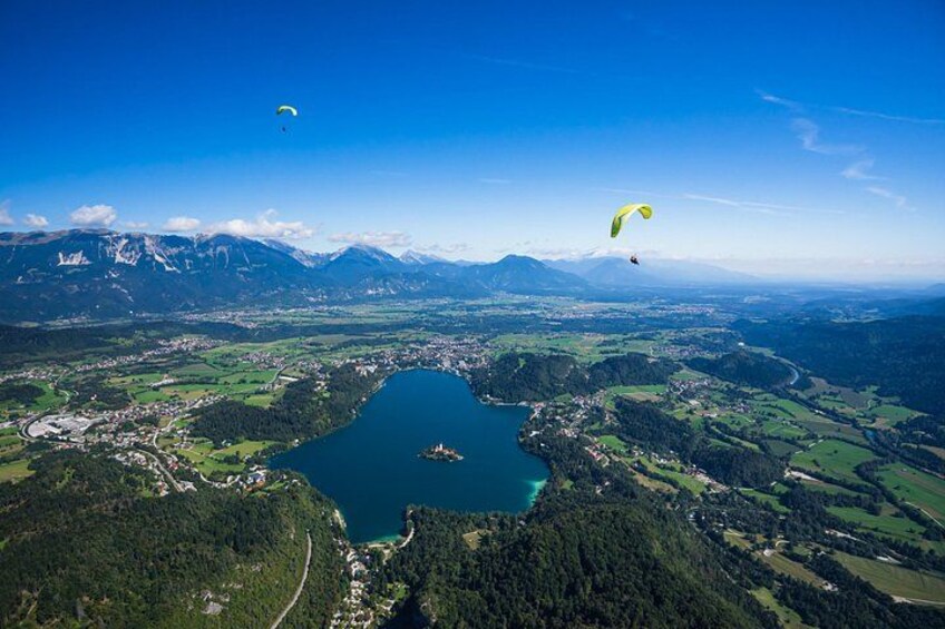 Un lac entouré de montagnes, une personne pratiquant le parapente et une autre personne en parachute. 1