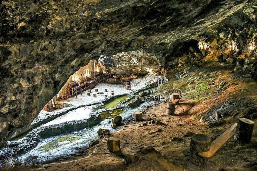 A cave with a river, wooden structures, and a rocky landscape. 5