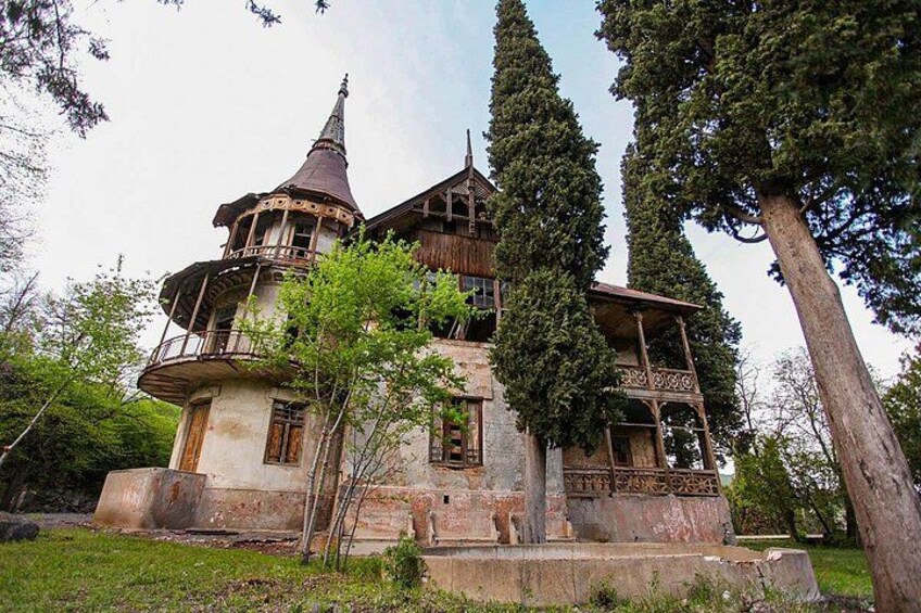 A historic building with a turret and balcony, surrounded by trees. 4