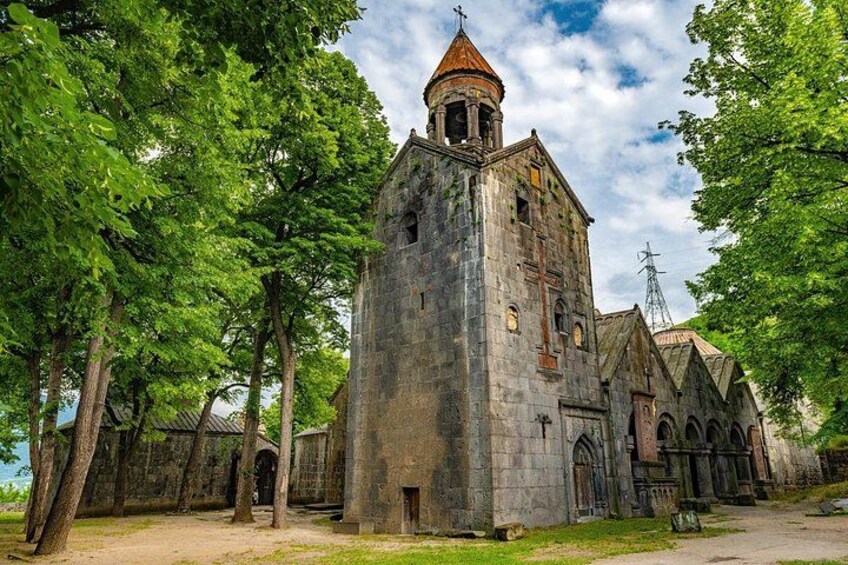A historic stone church with a bell tower, surrounded by trees. 2
