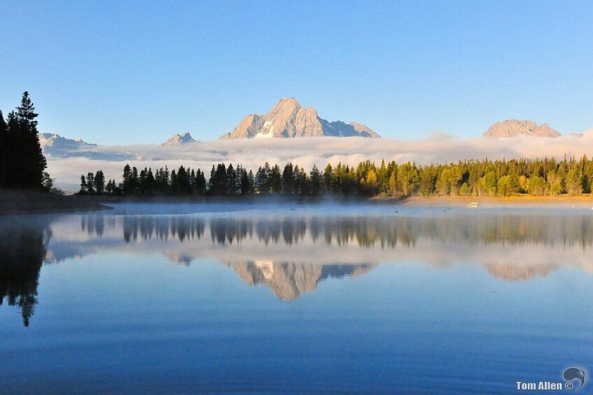 A calm lake reflecting mountains and trees. 3