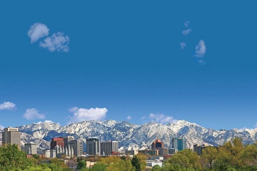 A city skyline with modern buildings and snow-capped mountains in the background. 3