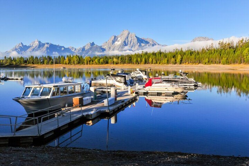 A calm lake with boats docked, surrounded by mountains and trees. 4