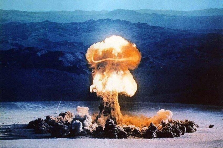 A nuclear explosion with a mushroom cloud, a crater, and a mountainous background. 3