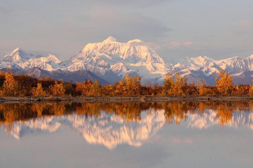 A mountain range reflected in a calm lake with autumn foliage. 5