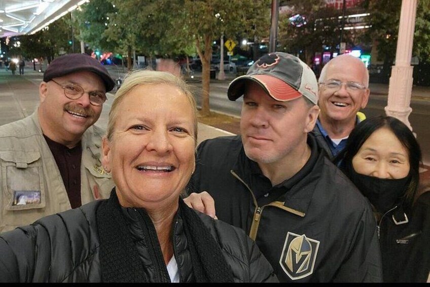 Eine Gruppe von Menschen draußen bei Nacht, im Hintergrund Bäume und Straßenlaternen. 4