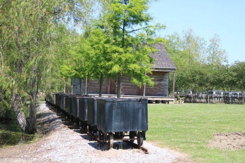 Eine Holzhütte, eine Reihe von Planwagen und ein Kiesweg. 5