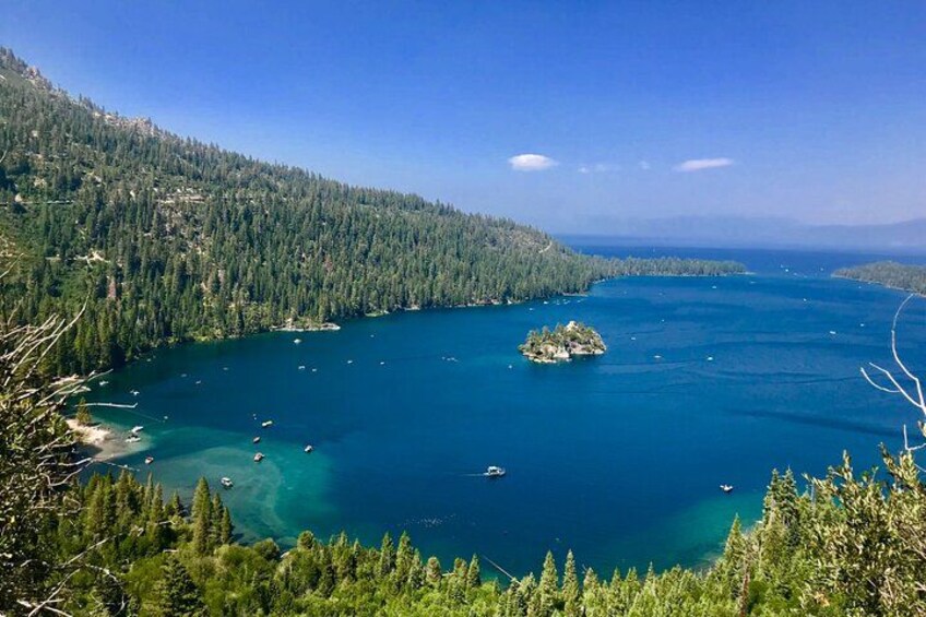 A coastal landscape with a forested hill, a small island, and clear blue waters. 3