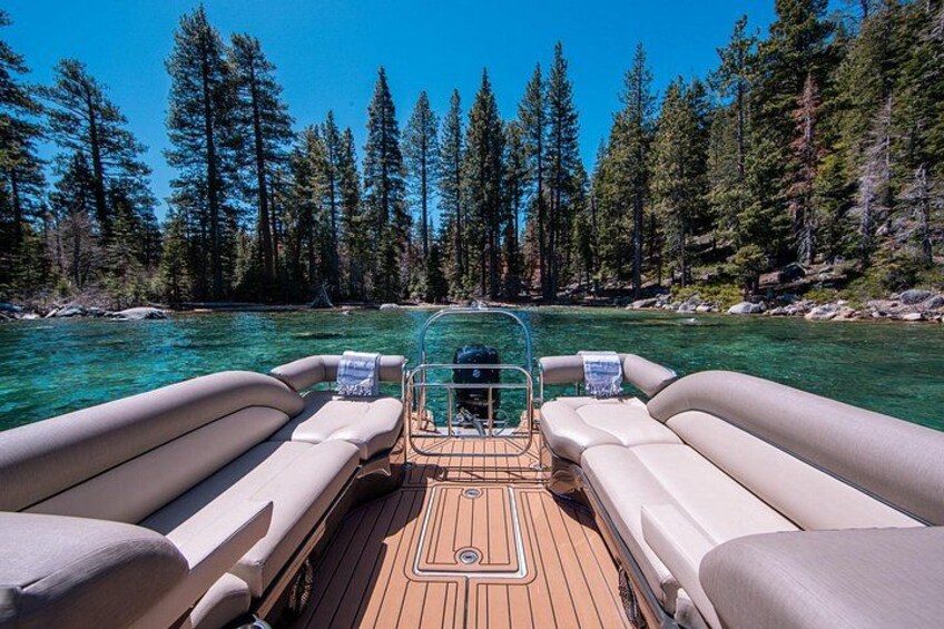 A boat with two cushioned seats and a wooden deck, surrounded by a clear river and dense forest. 2