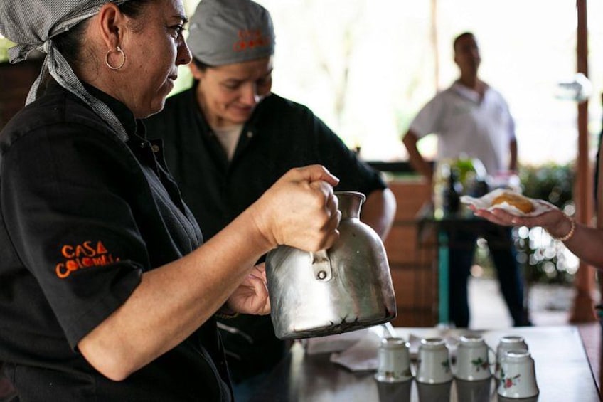 A person pouring liquid from a kettle into a cup. 4
