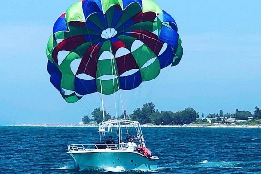 Une activité de parachute ascensionnel avec une voile colorée au-dessus d’un bateau sur l’eau. 1