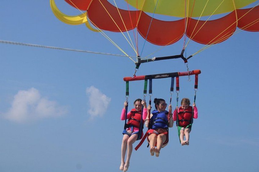 Un groupe de personnes pratiquant le parapente avec des parachutes aux couleurs vives, sur fond de ciel dégagé. 4