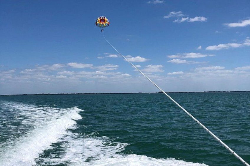 Une personne fait du parachute ascensionnel au-dessus de l’eau, sous un ciel dégagé. 3