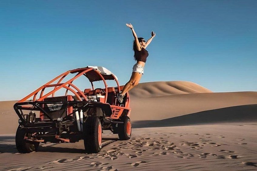 En sandbuggy i en öken med sanddyner i bakgrunden. 1
