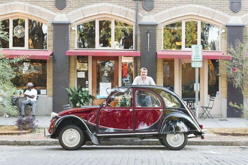 A vintage car parked in front of a building with a 'Pay Here' sign. 5