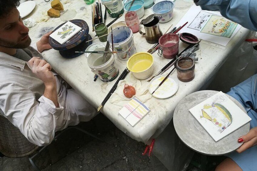 A person painting at a table with various art supplies. 1