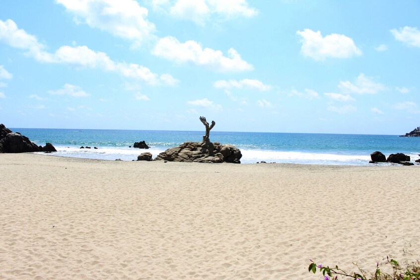 Una playa arenosa con grandes rocas y un cielo azul despejado. 5