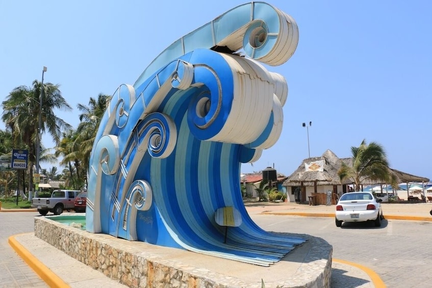 Escultura grande de una ola azul y blanca en un espacio público. 3