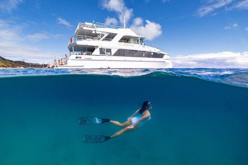 A person snorkeling underwater with a boat in the background. 1
