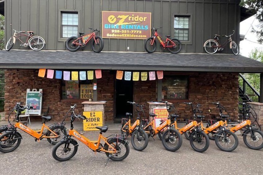 Un bâtiment avec une enseigne indiquant « EZ Rider Bike Rentals », plusieurs vélos garés devant et une façade en briques. 2