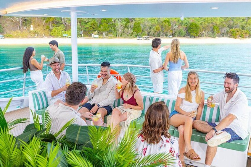 Un groupe de personnes se trouve sur un bateau, avec une plage tropicale en arrière-plan. 2