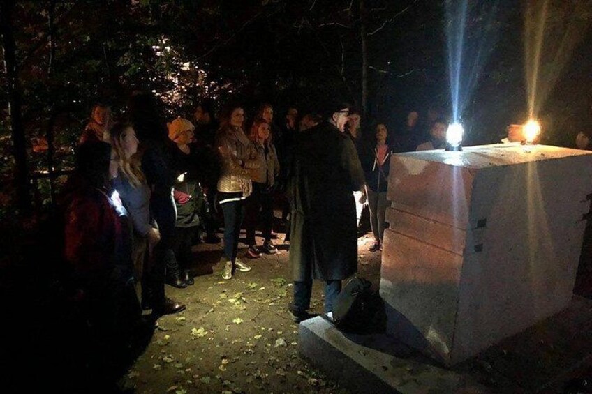 En gruppe mennesker samlet omkring et lysende stearinlys på en stensøjle om natten. 1